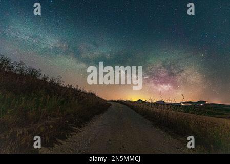 Vista notturna con via lattea di una strada di campagna nell'entroterra siciliano, in Italia Foto Stock