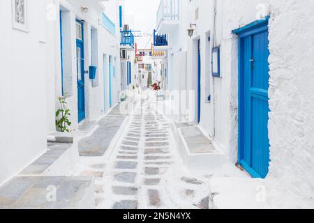 Mykonos, Grecia - tradizionale strada imbiancata di Mykonos città con finestre e porte blu in una soleggiata mattinata estiva. Vicolo vuoto all'alba Foto Stock