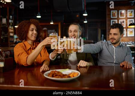 Allegri vecchi amici che si divertono e bevono birra alla spina nel bar dello sport Foto Stock