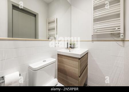 Bagno con lavandino in porcellana bianca su armadio in legno con cassetti, specchio  da parete a parete senza cornice e box doccia in vetro Foto stock - Alamy