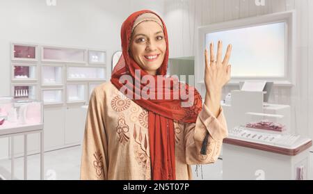 Donna che indossa un hijab e mostra un anello sul dito all'interno di una gioielleria Foto Stock