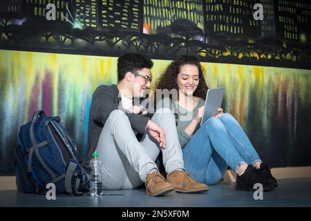 Studenti universitari con tablet digitale di fronte alla Graffiti Wall School, Baviera, Germania Foto Stock