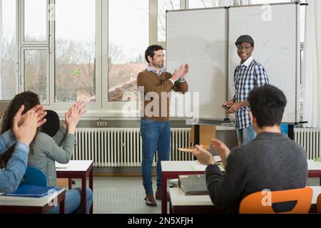 Studente universitario che finisce la presentazione in aula, studenti e insegnante Clapping School, Baviera, Germania Foto Stock