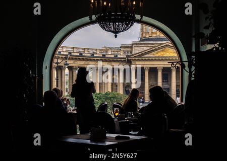 Vista della Cattedrale di Kazan dal Singer Cafe attraverso la finestra. Silhouette di persone sedute ai tavoli nella vecchia Singer House a San Pietroburgo, Russia. Foto di alta qualità Foto Stock