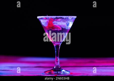 Bicchiere con acqua e frutta varia in luce al neon con spazio copia su sfondo nero Foto Stock