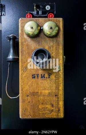 Antico legno di quercia di circa 1910 e nero bachelite piano parete frontale telefono con campanelli in ottone in garage all'interno della vecchia casa 1927. Foto Stock