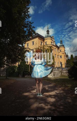 Bella giovane donna vestito blu con nuvole in un castello Foto Stock