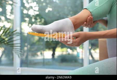 Donna che monta soletta ortopedica in interni, primo piano. Cura dei piedi Foto Stock