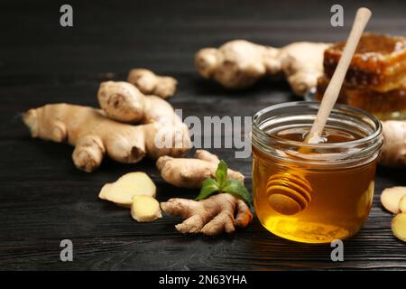 Miele e zenzero su tavola di legno nero. Rimedi freddi naturali Foto Stock