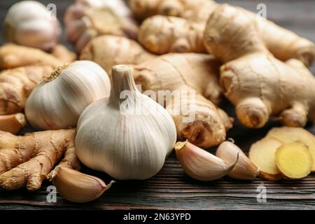 Zenzero e aglio su tavola di legno nero, spicchio. Rimedi freddi naturali Foto Stock