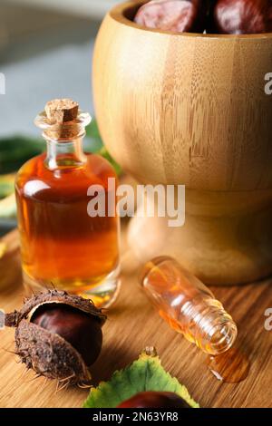 Castagne di cavallo, foglie e bottiglie di tintura su tavola di legno Foto Stock