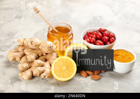 Scheda con parola immunità e prodotti freschi su sfondo marmo chiaro Foto Stock