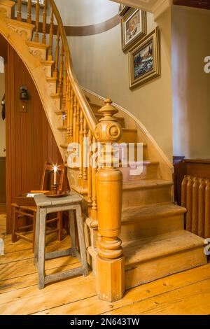 Scala curva in legno con palo di fantasia e balaustre al piano terra all'interno della vecchia casa in stile cottage del 1805 circa. Foto Stock