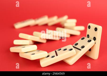 Piastrelle bianche domino che cadono su sfondo rosso Foto Stock