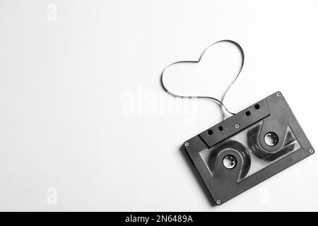Cassetta musicale e cuore realizzati con nastro su sfondo bianco, vista dall'alto. Ascoltare la canzone d'amore Foto Stock