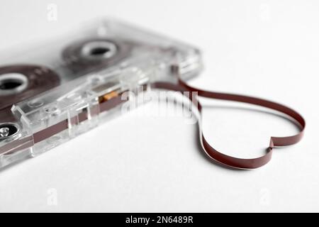 Cassetta musicale e cuore realizzati con nastro su sfondo bianco, primo piano. Ascoltare la canzone d'amore Foto Stock