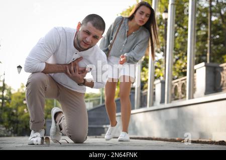 Uomo che ha un attacco di cuore vicino a una donna preoccupata sulla strada cittadina Foto Stock