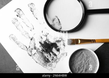Lente di ingrandimento e stampa sul palmo del tavolo, vista dall'alto. Luogo di lavoro del detective Foto Stock