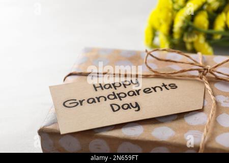 Confezione regalo e tag con frase giorno dei nonni felice su sfondo chiaro, primo piano Foto Stock