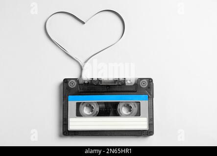 Cassetta musicale e cuore realizzati con nastro su sfondo bianco, vista dall'alto. Ascoltare la canzone d'amore Foto Stock