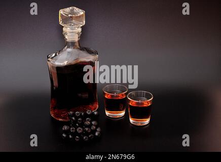 Liquore di chokeberry fatto in casa su sfondo nero. Primo piano. Foto Stock