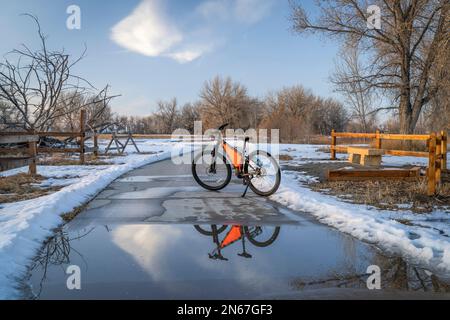 Mountain bike sul Poudre River Trail vicino a Greeley in Colorado, scenario invernale con la riflessione delle pozzanghere Foto Stock