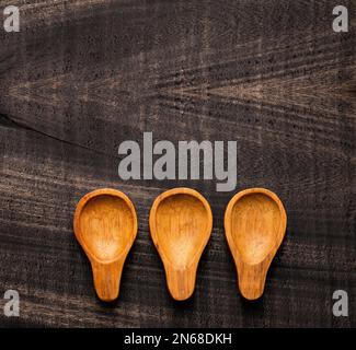 Tre cucchiai di legno su tavolo rustico scuro - Accessori cucina Foto Stock