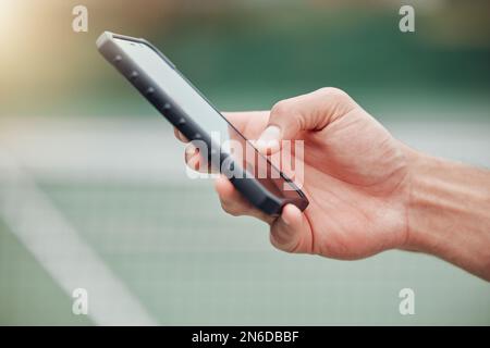 Primo piano di sconosciuto giocatore di tennis di razza mista utilizzando il cellulare durante la pausa in gioco sul campo. Atleta ispanico in forma che naviga in Internet e in rete su Foto Stock