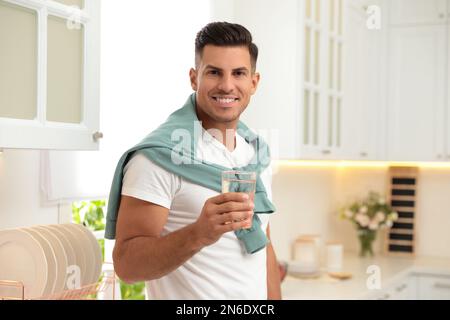 Uomo che tiene un bicchiere d'acqua pura in cucina Foto Stock