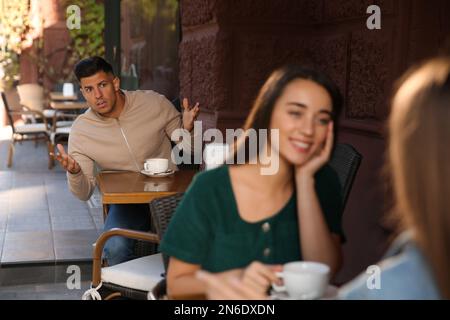 Uomo geloso che spionava sulla ex fidanzata nel caffè all'aperto Foto Stock