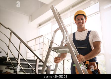 Costruttore professionale con scala in metallo sulle scale Foto Stock