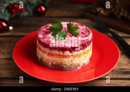 Aringa sotto pelliccia servita su tavolo di legno, guardaroba. Insalata russa tradizionale Foto Stock