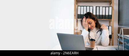 Dispiaciuta medico stanco utilizzando il computer e leggendo una e-mail presso l'ufficio medico. Medico iperlavorato con mal di testa riposante in ufficio moderno, medicina Foto Stock
