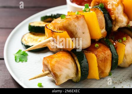 Deliziosi kebab di pollo shish con verdure su tavolo di legno, primo piano Foto Stock