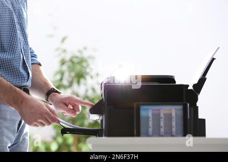 Dipendente che utilizza una stampante moderna in ufficio, in primo piano Foto Stock