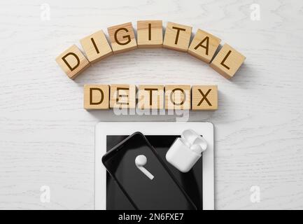 Diversi gadget e cubi con parole DETOX DIGITALE su sfondo di legno bianco, piatto Foto Stock