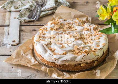 Torta di rabarbaro con farcitura di meringa e mandorle tostate su un vecchio tavolo rustico in legno Foto Stock