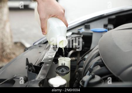 Uomo che riempie il radiatore dell'automobile con antigelo all'aperto, primo piano Foto Stock