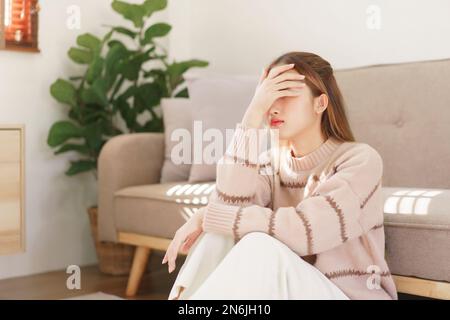 Concetto di tempo di riposo, le donne sono sedute sul pavimento e toccare la fronte dolorante con mal di testa sofferenza. Foto Stock