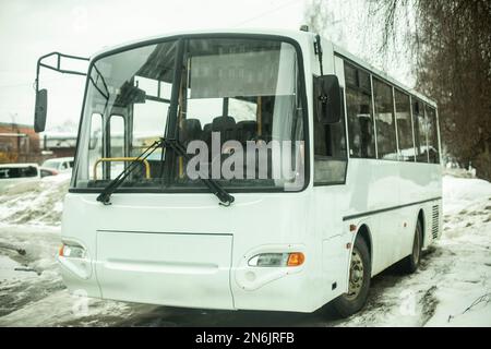 Autobus bianco nel parcheggio. Trasporto pubblico in inverno. Auto sulla strada. Foto Stock