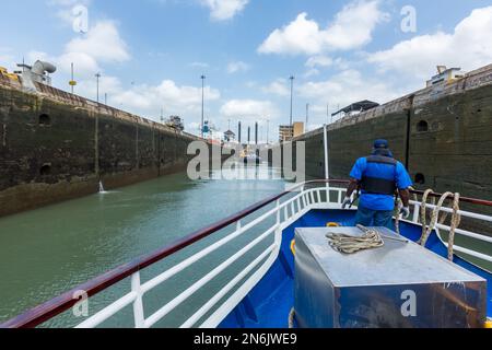 Un tour in barca entra nella camera di chiusura presso le chiuse di Miraflores sul canale di Panama. Un rimorchiatore e una draga sono già nella camera di chiusura. Foto Stock