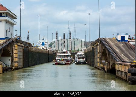 Le barche del tour e un drago condividono lo spazio nella camera della serratura presso le chiuse di Pedro Miguel. Canale di Panama, Panama. Foto Stock