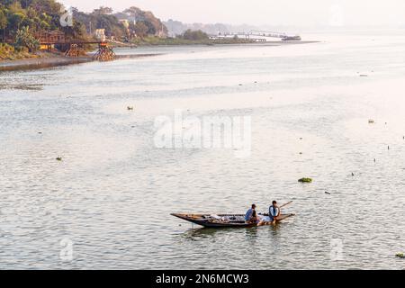 Pescatori locali che pescano con le reti da una piccola barca a remi di legno nel fiume Hooghly, Serampore, vicino Calcutta, Bengala Occidentale, India alla luce della sera Foto Stock