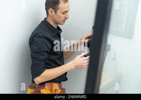 Plumber installazione di una cabina doccia in bagno Foto Stock