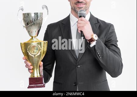 felice uomo maturo in tuta tiene campione coppa e microfono isolato su sfondo bianco. Foto Stock