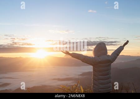 Donna cristiana mani di pregare dio sullo sfondo di montagna con l'alba mattina, Carefree Happy Woman godendo la natura in cima alla scogliera di montagna Foto Stock