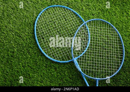 Racchette da badminton su erba verde all'aperto, vista dall'alto. Spazio per il testo Foto Stock