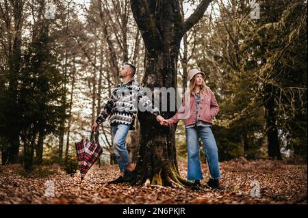 Una coppia innamorata si trova accanto ad un albero in un parco autunnale, Foto Stock