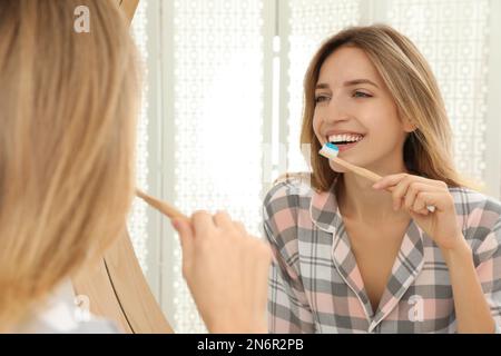 Donna spazzolare i denti vicino allo specchio in bagno Foto Stock