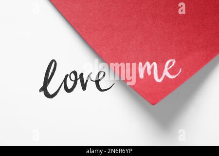 Frase Love Me scritto su carta bianca e rossa Foto Stock